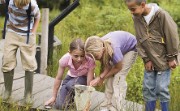 Group of children pond-dipping on a small bridge